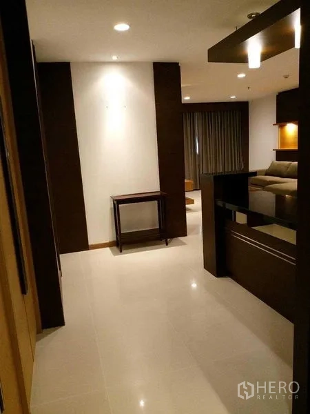 คอนโด ให้เช่าในSathon, Bangkok - โถงทางเข้าปูพื้นกระเบื้องเงา โทนไม้เข้มและไฟดาวน์ไลท์สู่ห้องนั่งเล่น