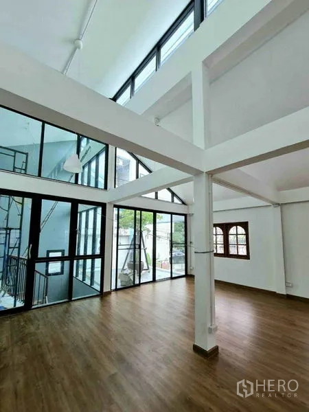 Home Office for rent in Lat Phrao, Bangkok - Upper floor studio with double-height ceiling, floor-to-ceiling windows, and wood floors.