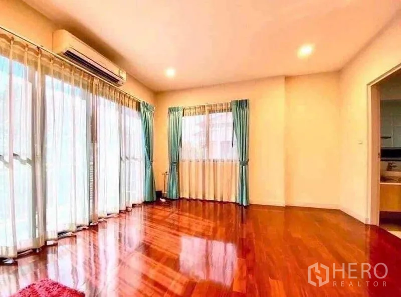 Detached House for sale in Saphan Sung, Bangkok - Sunlit corner room with glossy wooden floors, big windows, sheer curtains and air conditioner.