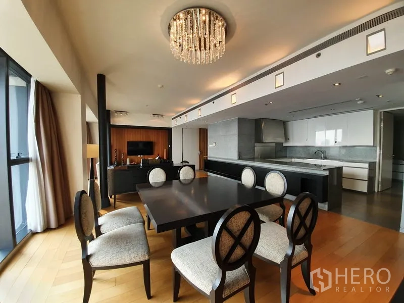 Condominium for rent in Sathon, Bangkok - Dining area with crystal chandelier beside an open-plan kitchen with island.