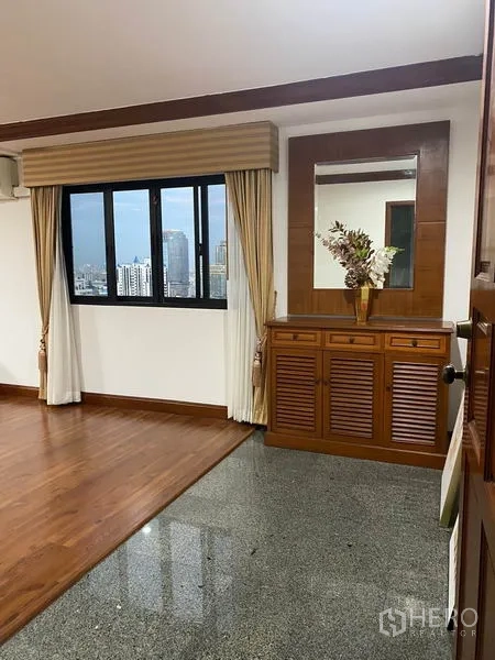 Condominium for rent in Watthana, Bangkok - Entrance foyer with console cabinet, large wall mirror and window framing skyline views.
