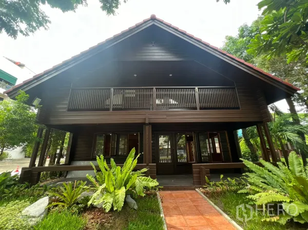 带办公室的家 出租在Suan Luang, Bangkok - 木屋式家用办公室正面，斜顶与二层阳台，庭院景观整洁。