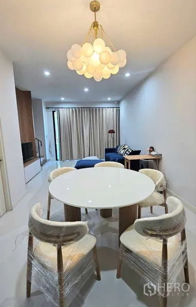 Townhouse for rent in Suan Luang, Bangkok - Dining zone with round table, statement chandelier and view toward the living room.