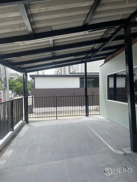 Townhouse for sale - Covered carport with metal roof and black fence at the front of the house