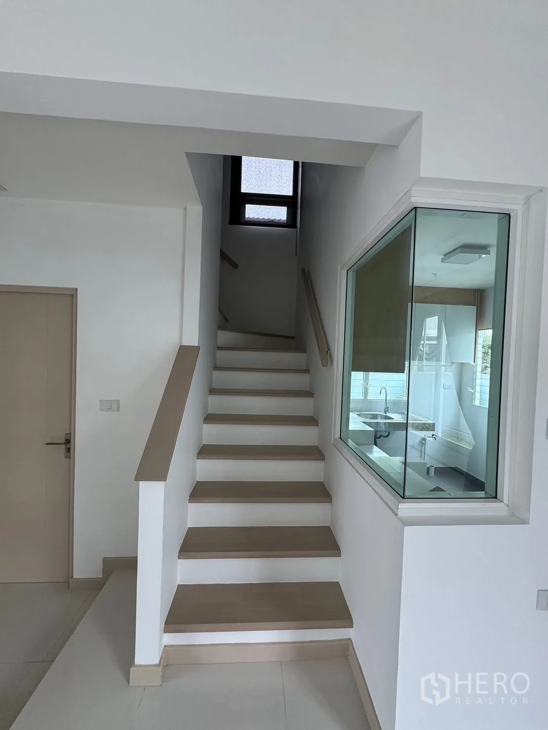 Detached House for rent in Bang Phli, Samut Prakan - Staircase with handrail and a glass window looking into the kitchen.