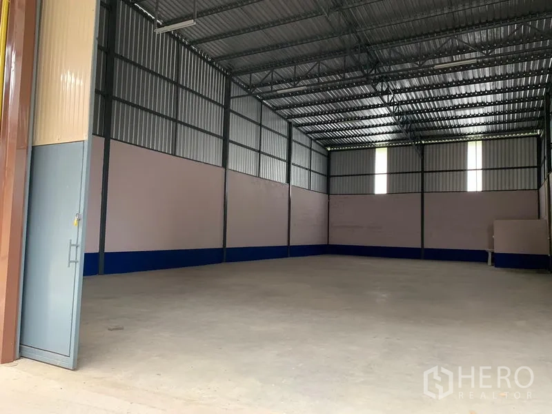 Warehouse for rent in Saphan Sung, Bangkok - Interior of an empty high-ceiling steel-frame warehouse in Saphan Sung, Bangkok, with concrete floor and skylight panels.