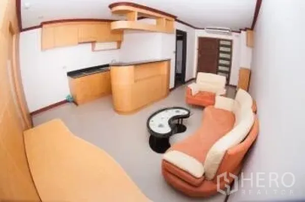 Condominium for sale in Watthana, Bangkok - Open-plan living room with curved sofa, built-in kitchen and a breakfast bar.
