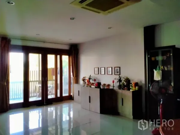 独立式住宅 出售在Thawi Watthana, Bangkok - 明亮客厅，亮面地砖，木框玻璃门通向露台。