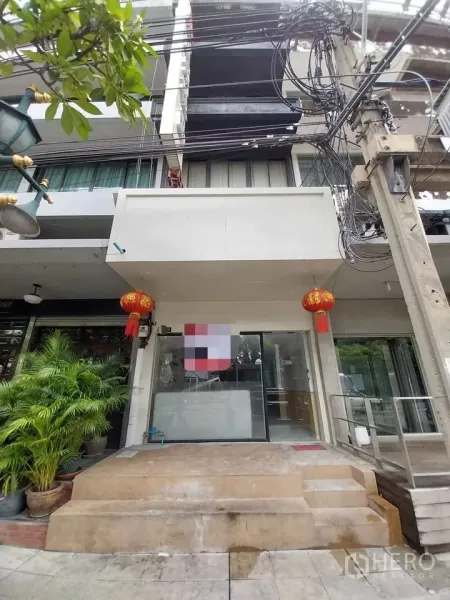 Shophouse for rent or sale in Watthana, Bangkok - Street-front shophouse facade on Sukhumvit 55 with glass door and red lanterns.