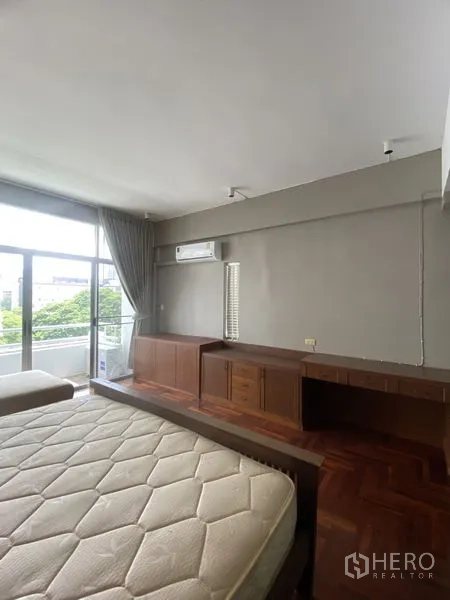 公寓 出租在Sathon, Bangkok - 宽敞卧室配长书桌与矮柜，壁挂空调，推拉门连接阳台。