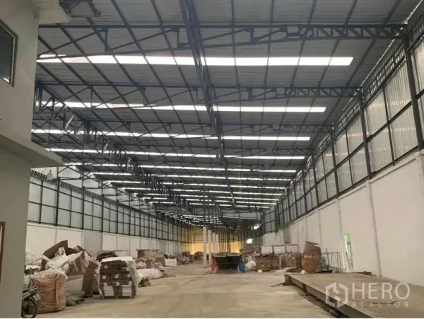 Warehouse for rent in Nakhon Pathom - Spacious warehouse interior in Don Tum, Nakhon Pathom with high steel truss roof, skylight panels, and a wide concrete drive aisle.