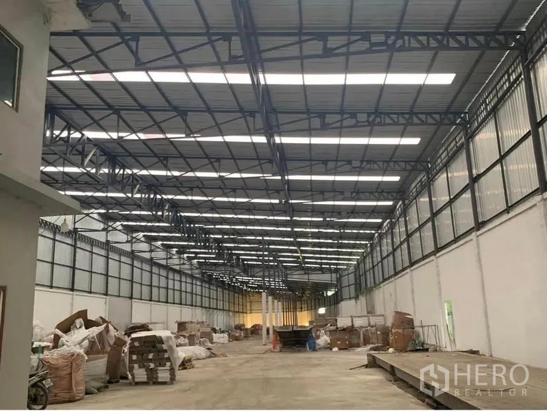 Warehouse for rent in Nakhon Pathom - Spacious warehouse interior in Don Tum, Nakhon Pathom with high steel truss roof, skylight panels, and a wide concrete drive aisle.