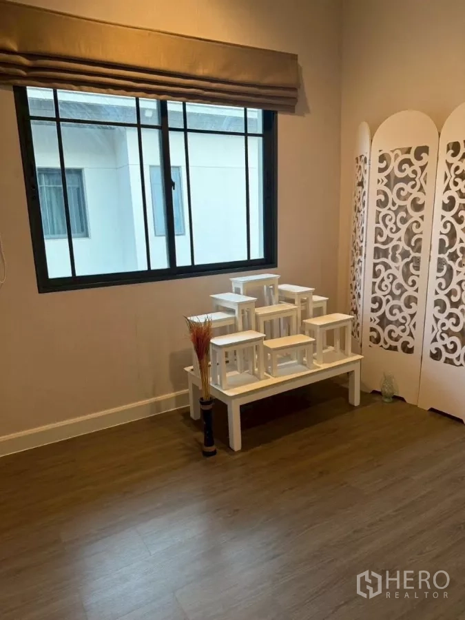 Detached House for rent or sale in Bang Phli, Samut Prakan - Multipurpose room with wood flooring, side window, white tiered altar stand and decorative partition.