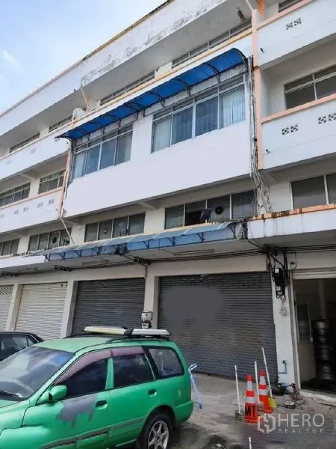 Shophouse for sale in Pathum Thani - Street-facing shophouse exterior with closed shutters and parking area.