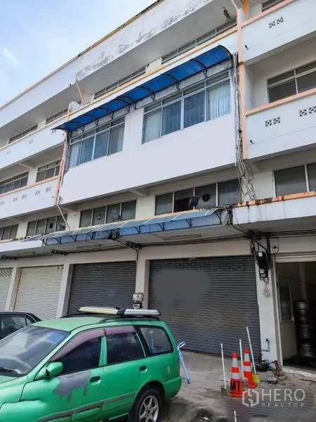 Shophouse for sale in Pathum Thani - Street-facing shophouse exterior with closed shutters and parking area.