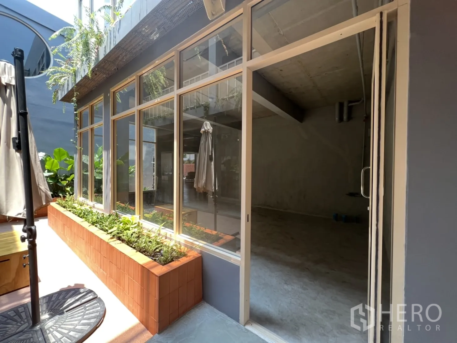 Retail Space for rent in Watthana, Bangkok - Close-up of retail unit entrance with full-height glass door and terracotta planter by the patio.