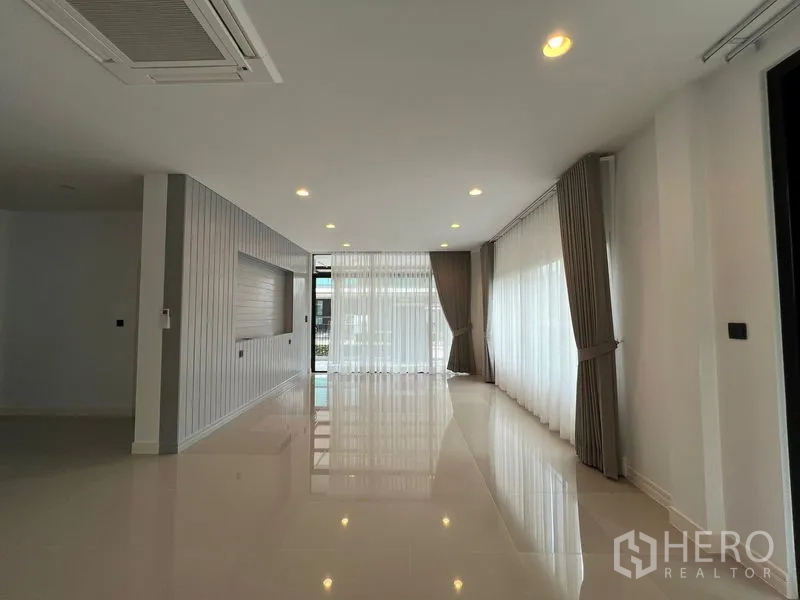 Detached House for rent in Bang Kapi, Bangkok - Long living and dining space with floor-to-ceiling curtains and feature wall.