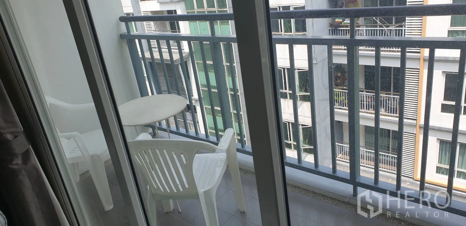 公寓 出租在Khlong Toei, Bangkok - 纤窄阳台，配圆桌与两把椅子，可见邻近建筑。