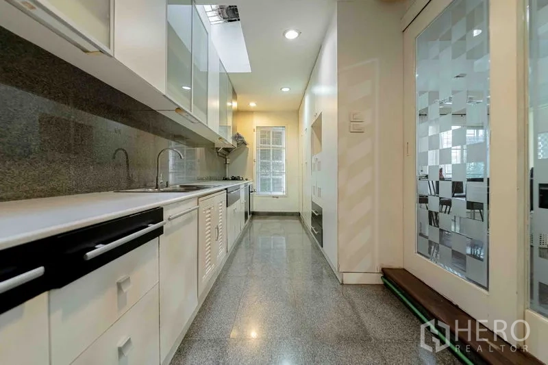 带办公室的家 出租在Bang Rak, Bangkok - 长形一字厨房，白色橱柜与石质台面，燃气灶，玻璃隔断门。