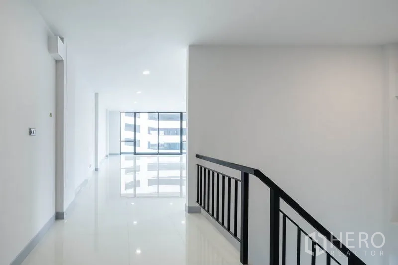 带办公室的家 出租在Bang Rak, Bangkok - 走廊配黑色金属扶手，通向通透明亮的办公区。