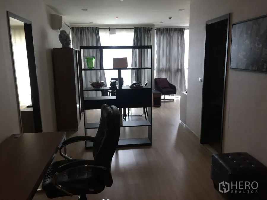 公寓 出租在Watthana, Bangkok - 开放式客厅，木地板，置物隔断与工作桌，落地窗配薄纱窗帘的曼谷公寓室内。