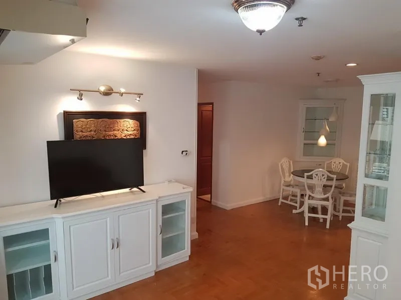 Condominium for rent or sale in Watthana, Bangkok - TV console and storage cabinet facing a cozy dining nook with round table and accent lighting.