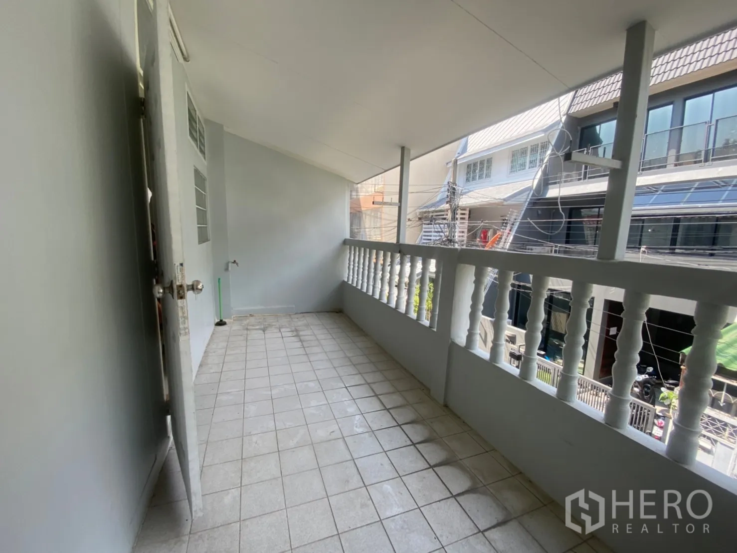 Townhouse for rent in Watthana, Bangkok - Upper-floor balcony corridor with white balustrade overlooking the neighborhood.