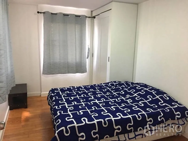 公寓 出租或出售在Yan Nawa, Bangkok - 卧室采光明亮，蓝色图案床品、木地板、灰色窗帘与推拉衣柜。