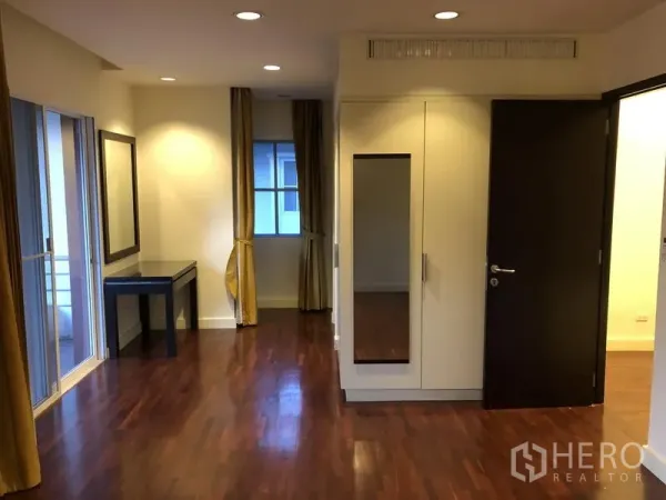 Detached House for rent in Wang Thonglang, Bangkok - Bedroom with wooden floors, built-in wardrobe with mirror, and balcony doors.