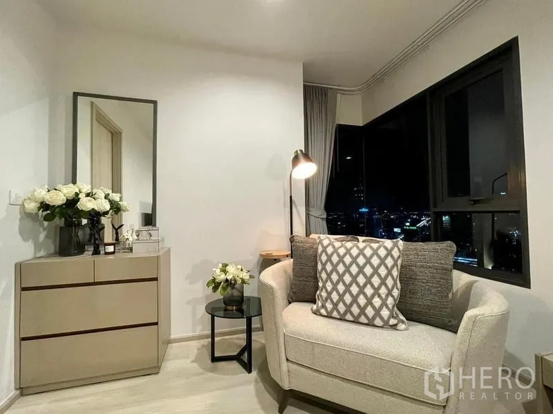 公寓 出租在Pathum Wan, Bangkok - 舒适阅读角，单人沙发、落地灯、斗柜与全景夜景窗。