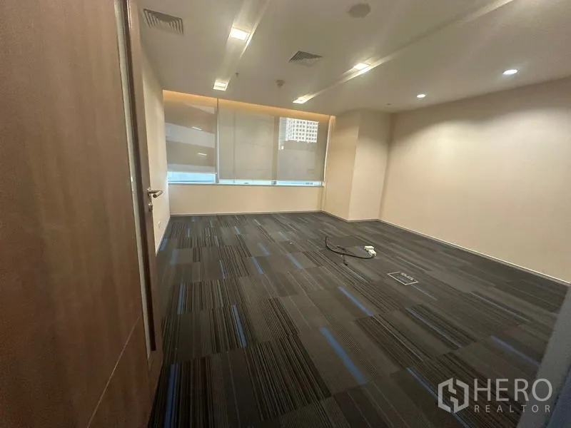 Office Space for rent in Khlong Toei, Bangkok - Private room with carpet tiles, recessed lighting, and a city-facing window.