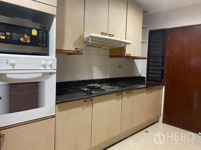 Condominium for rent in Watthana, Bangkok - Closed kitchen with gas hob, range hood and built-in oven and microwave.