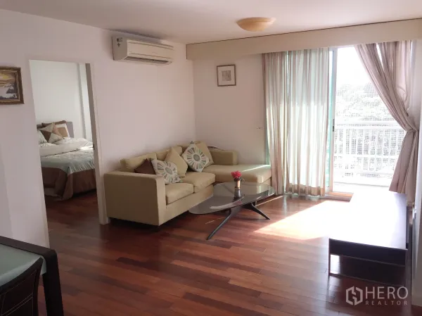 คอนโด ให้เช่าในWatthana, Bangkok - ห้องนั่งเล่นสว่างด้วยประตูกระจกบานเลื่อนสู่ระเบียง โซฟาและโต๊ะกลาง