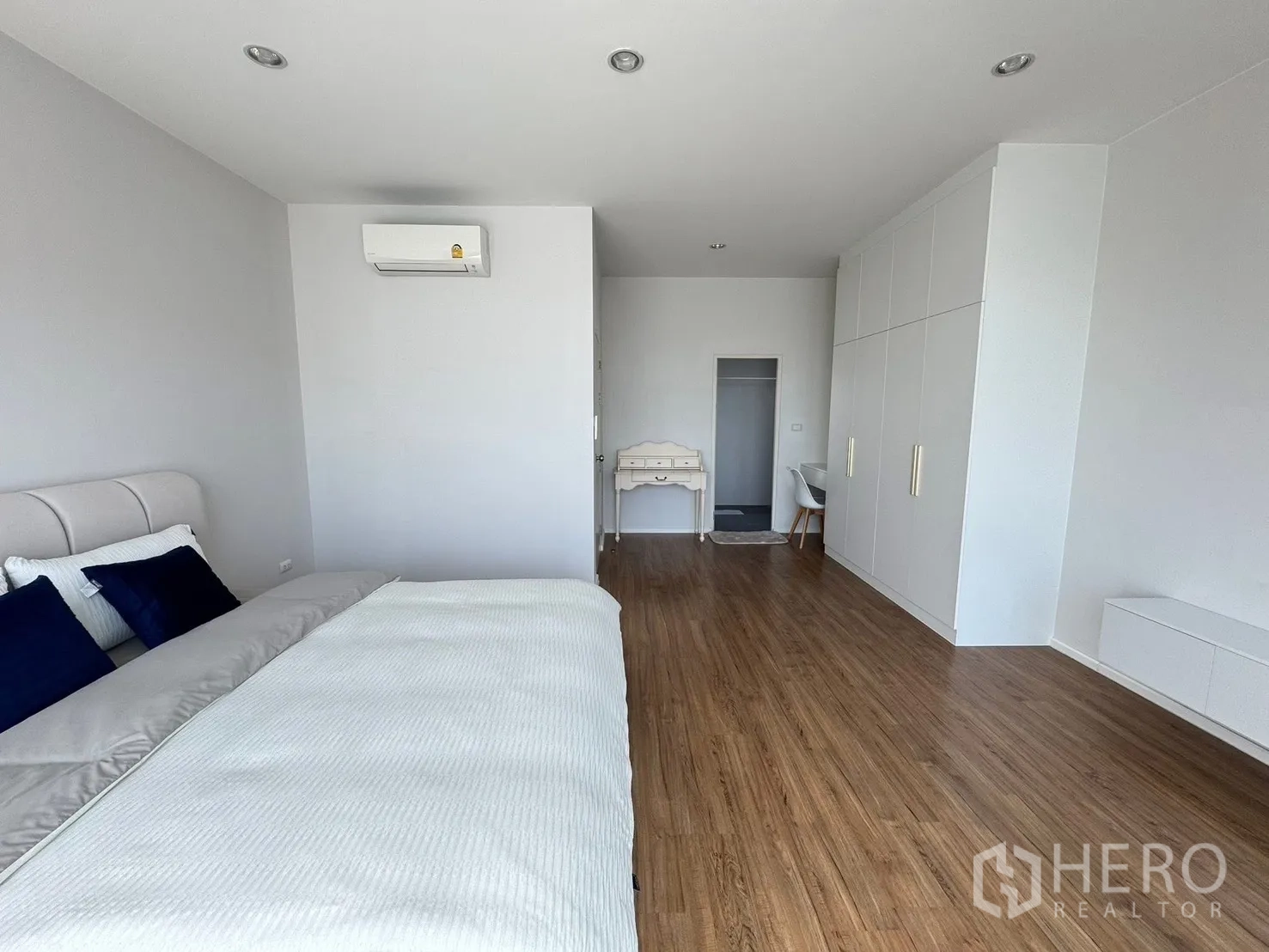 Townhouse for rent in Saphan Sung, Bangkok - Spacious master bedroom with wood flooring, built-in wardrobes, desk and air-conditioning.