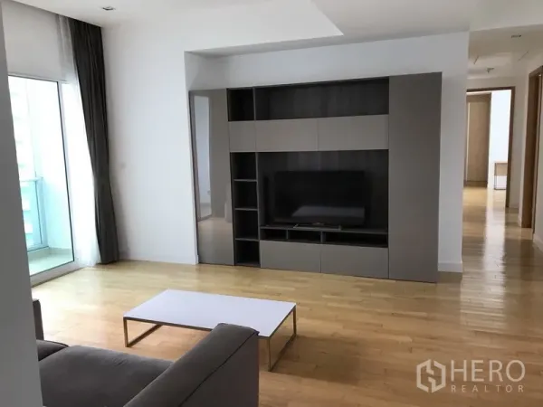 Condominium for rent in Khlong Toei, Bangkok - Living area with built-in media wall, TV unit and hardwood floors in a modern Bangkok condo.