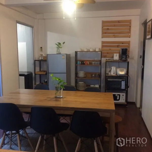 独立式住宅 出租在Sathon, Bangkok - 用餐区配长木桌、黑色餐椅与开放式置物架小厨房。