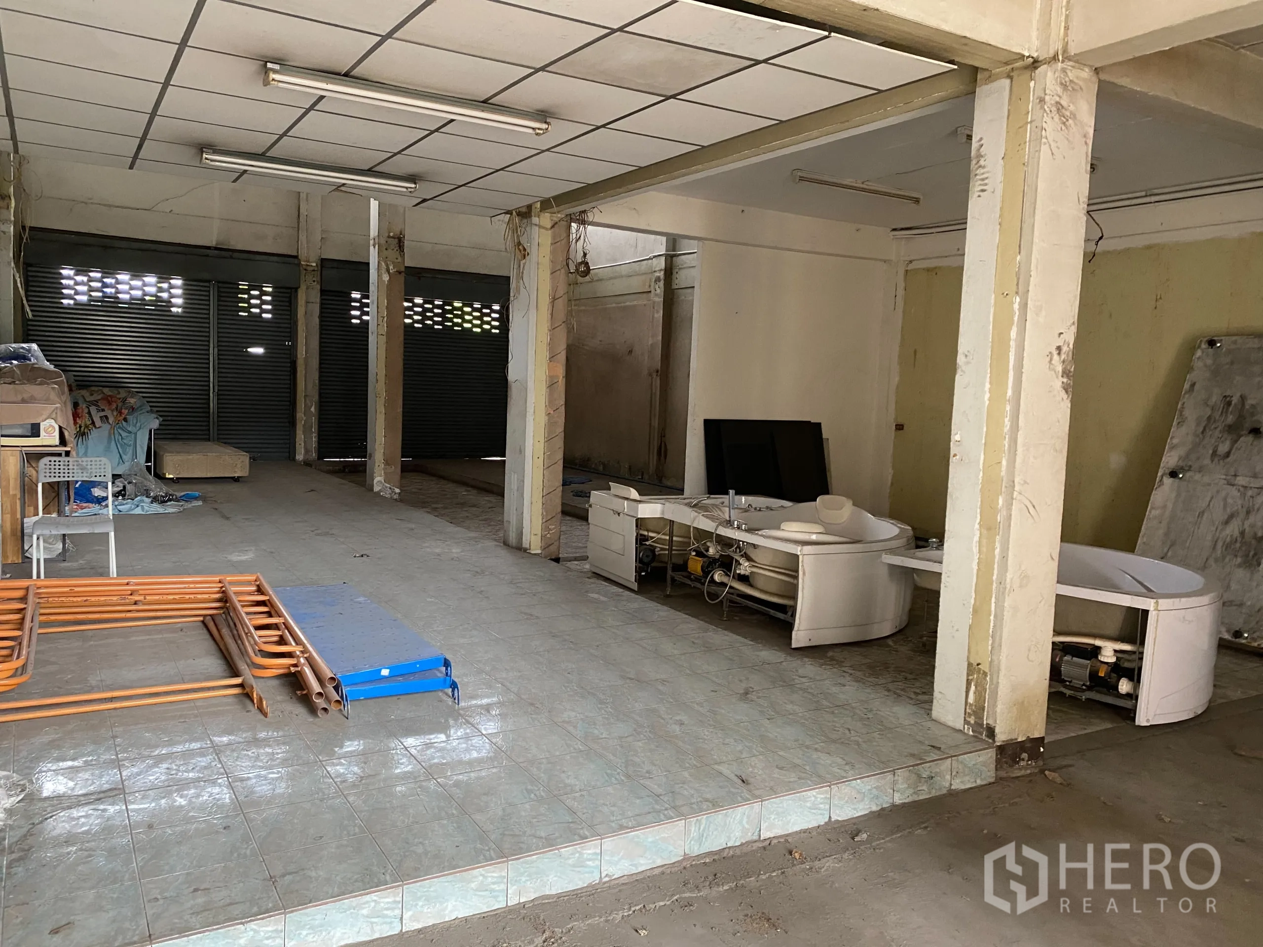 Retail Space for rent in Yan Nawa, Bangkok - Deep shop space with tiled platform, multiple roller shutters and fluorescent lighting.