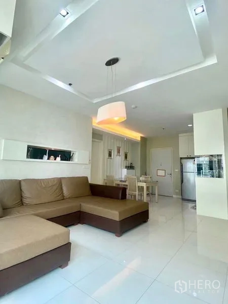 公寓 出租或出售在Bang Kapi, Bangkok - 开放式客厅，L形沙发、吊灯与亮面白色地砖。