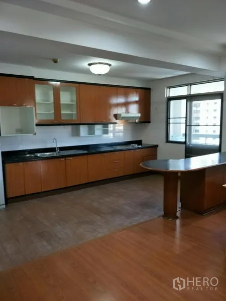 公寓 出租在Watthana, Bangkok - 全尺寸厨房，长黑色台面、木质橱柜与早餐岛，采光充足。