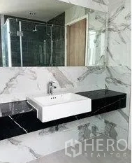 Home Office for rent in Don Mueang, Bangkok - Modern bathroom with marble-look walls, large mirror, black stone vanity and a glass shower.