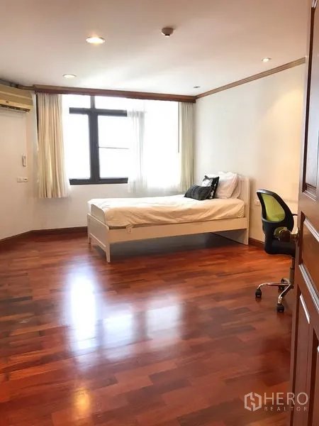 公寓 出租在Watthana, Bangkok - 宽敞的多功能房，配单人床、窗户与木地板