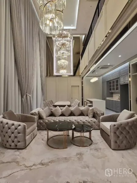 Detached House for rent or sale in Bang Kapi, Bangkok - Double-volume living room with towering crystal chandeliers, tufted sofas and an open kitchen.