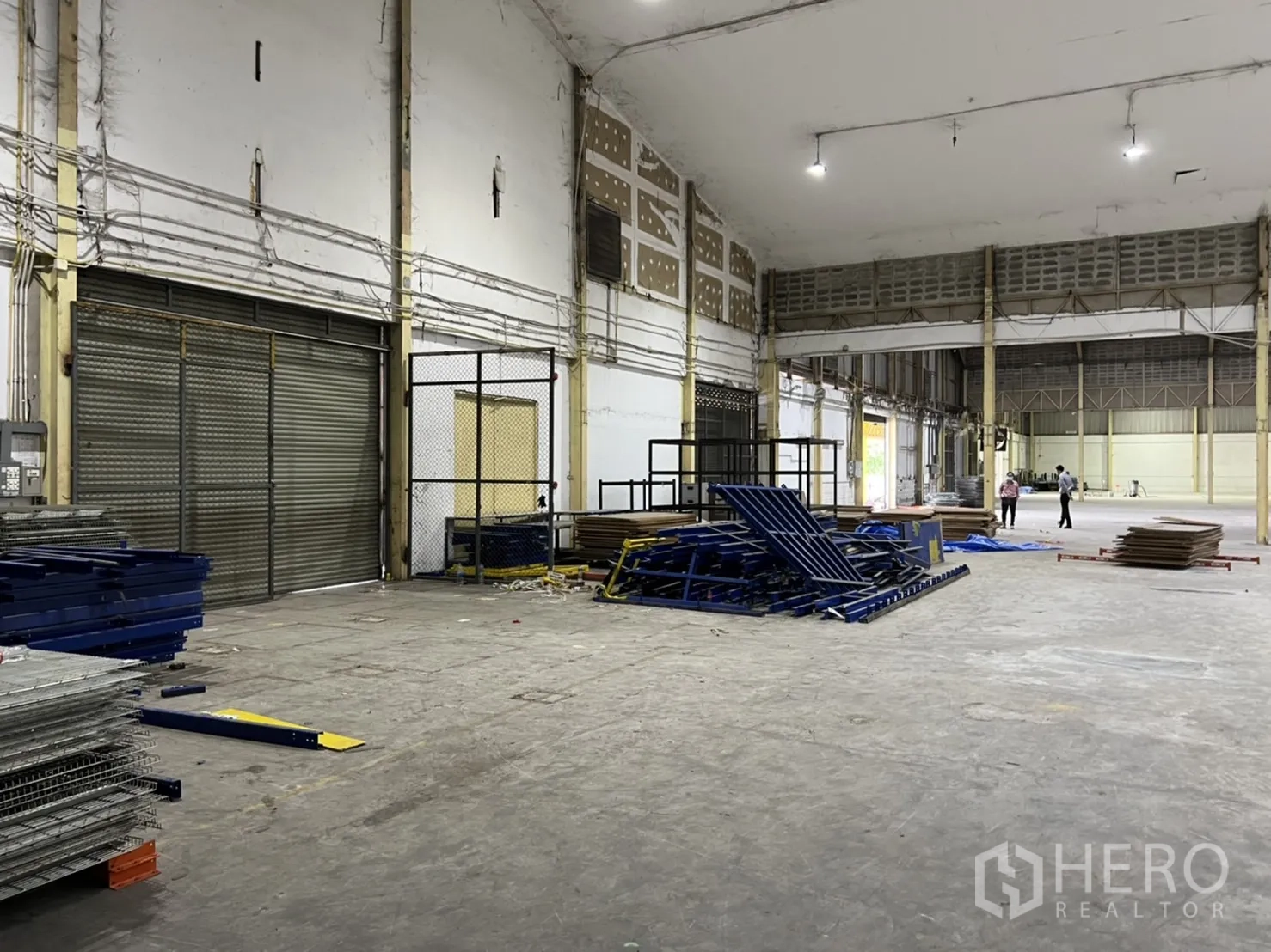 Warehouse for rent in Mueang Samut Prakan, Samut Prakan - Storage area inside the warehouse with a roller shutter door and steel racks.