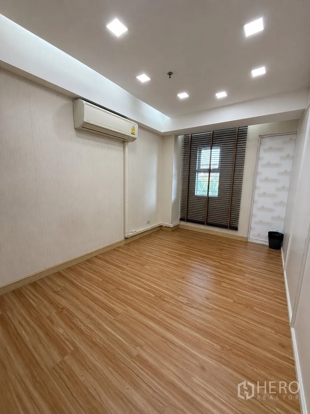 家庭办公室 for rent or sale in Yan Nawa, Bangkok - 空房间配木地板、筒灯、空调与窗户。