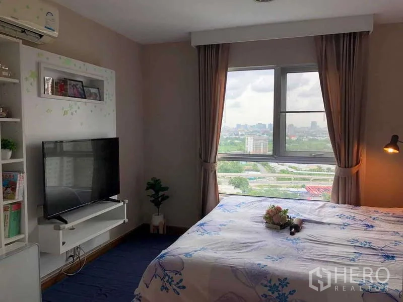 คอนโด ขายในHuai Khwang, Bangkok - อีกมุมของห้องมาสเตอร์ โชว์วิวเมืองผ่านหน้าต่างกว้างและชั้นวางทีวี
