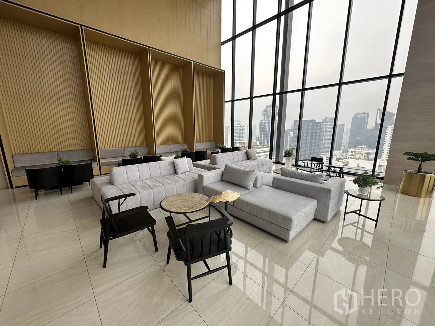 公寓 出租在Watthana, Bangkok - 典雅会客区，组合沙发与落地窗，背景为天际线