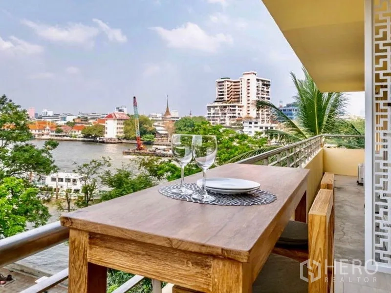 公寓 出租或出售在Khlong San, Bangkok - 河景阳台配木质餐桌，可观湄南河与城市天际线