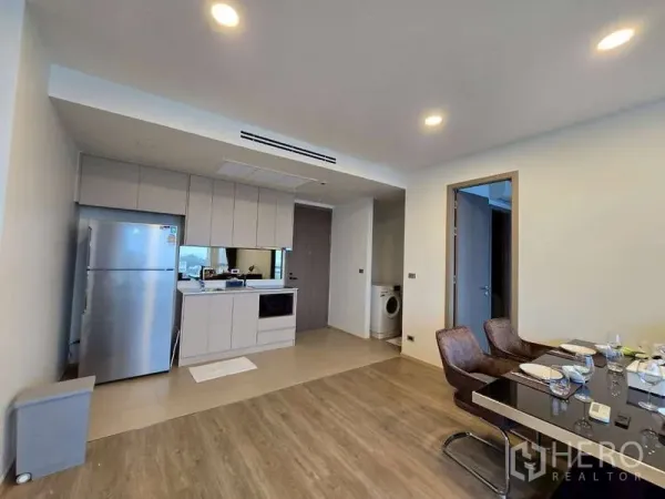 公寓 出租在Phaya Thai, Bangkok - 现代开放厨房，含不锈钢冰箱、嵌入式炉灶与餐区，可见洗衣角。
