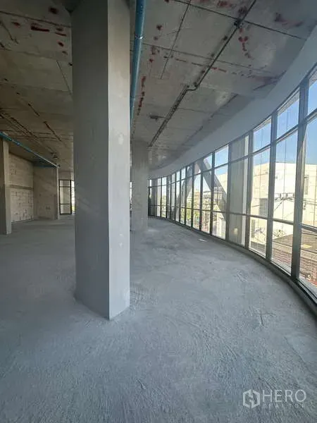 Retail Space for rent in Phra Khanong, Bangkok - Curved wall of floor-to-ceiling glass giving panoramic street views inside an unfinished retail space.