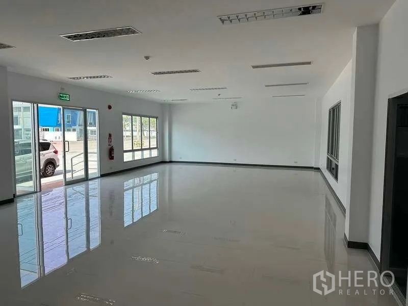 Factory for rent in Bang Sao Thong, Samut Prakan - Sunlit office lobby with windows and glass entrance facing the parking area.